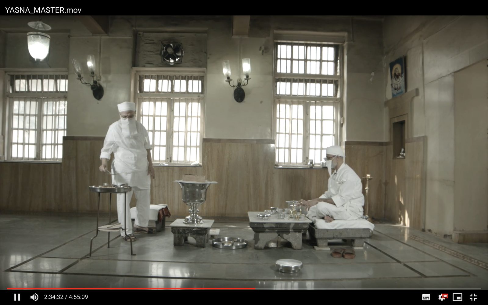 Film still: two Zoroastrian priests in white performing the Yasna ceremony